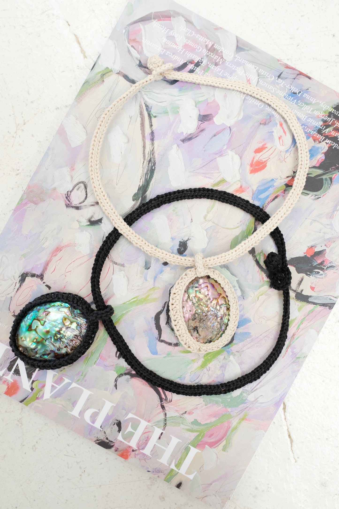 Necklace with abalone shell pendants on a colorful magazine background. Beklina Caged Abalone Necklace.