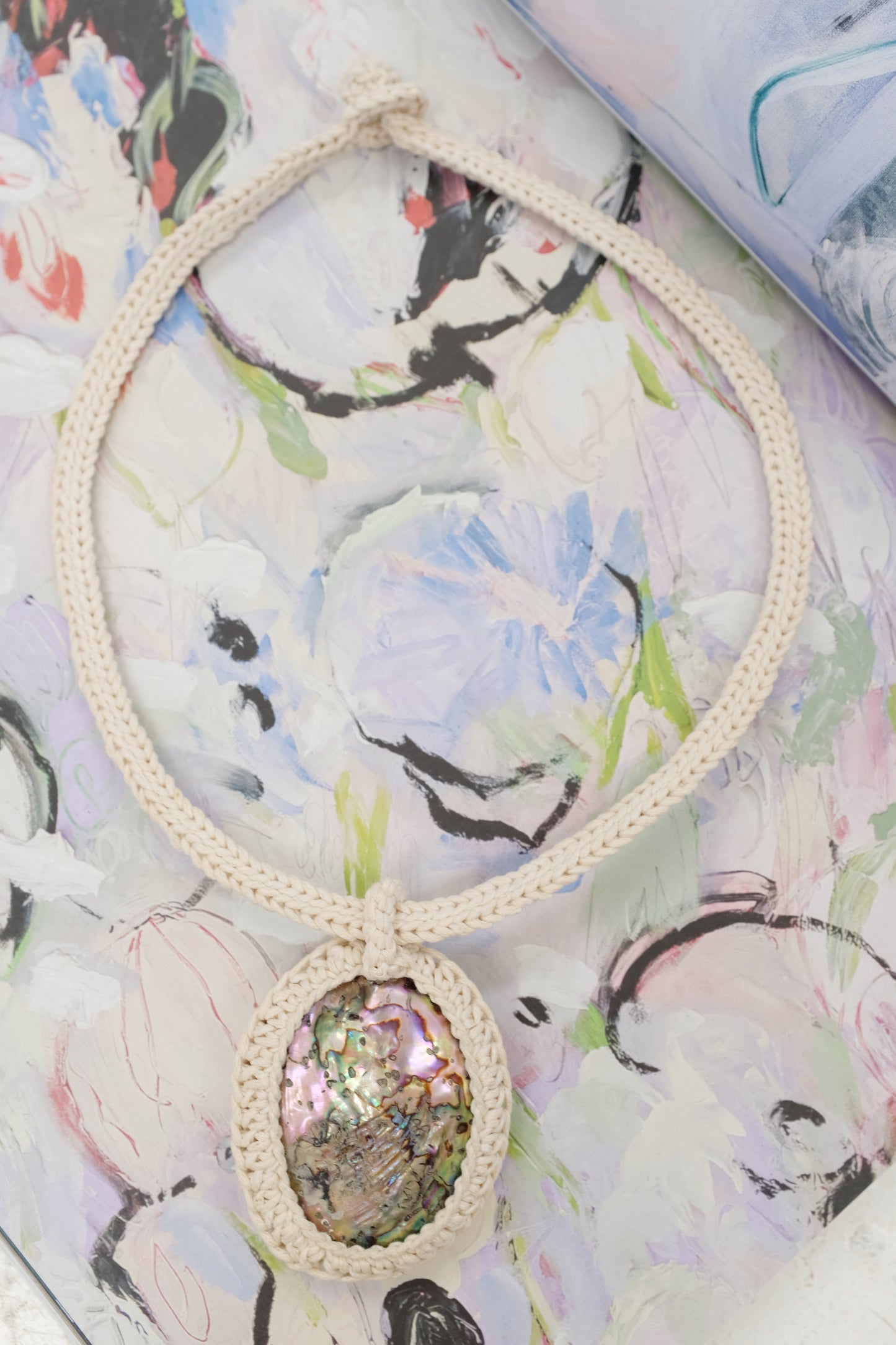 Necklace with abalone shell pendants on a colorful magazine background. Beklina Caged Abalone Necklace.