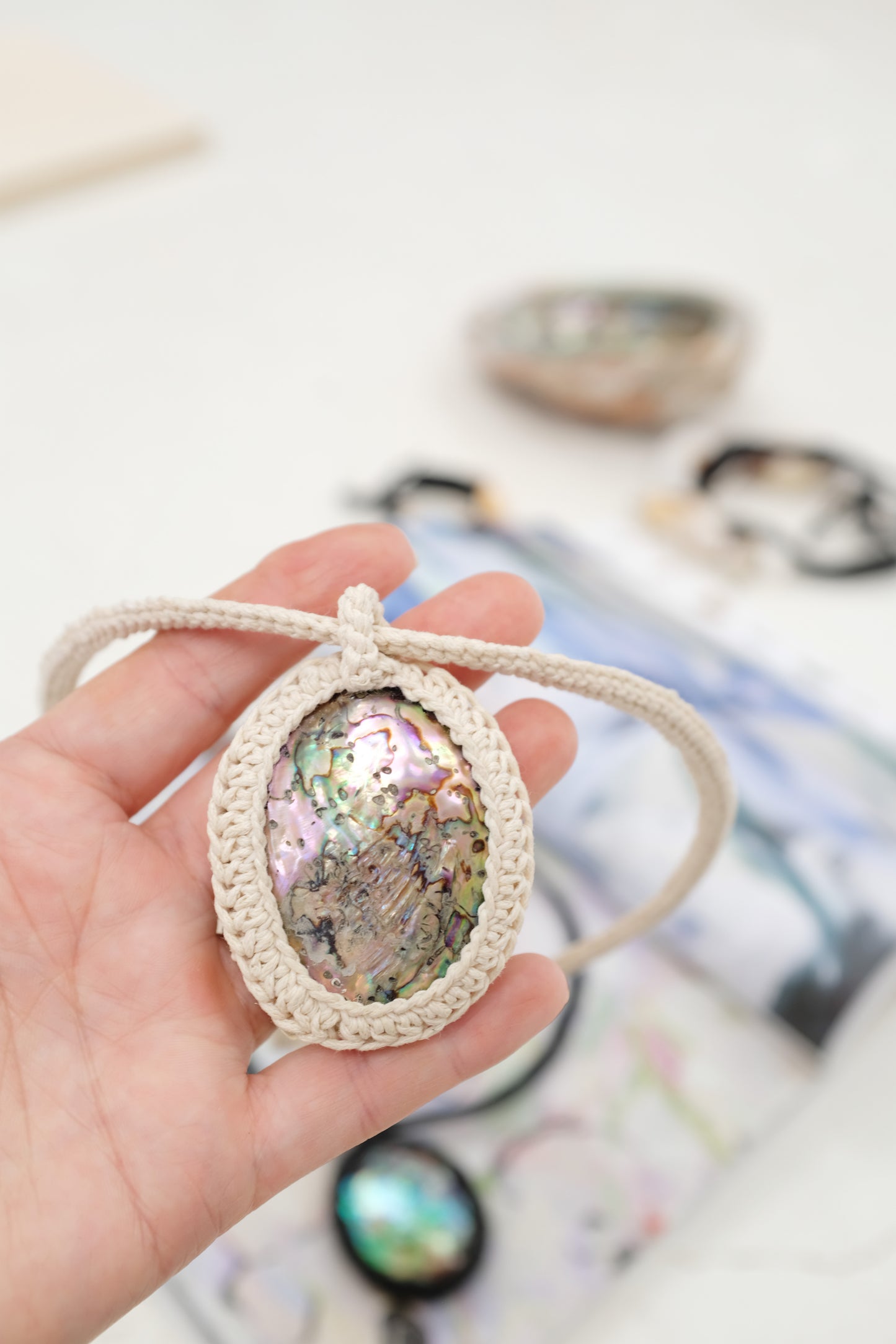 Necklace with abalone shell pendants on a colorful magazine background. Beklina Caged Abalone Necklace.