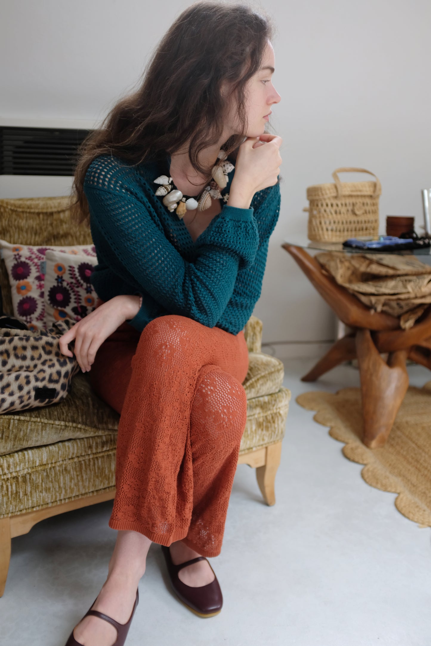 A model wearing a terracotta-colored, hand knitted floral cotton lace pant with a straight leg and gentle elastic waist.